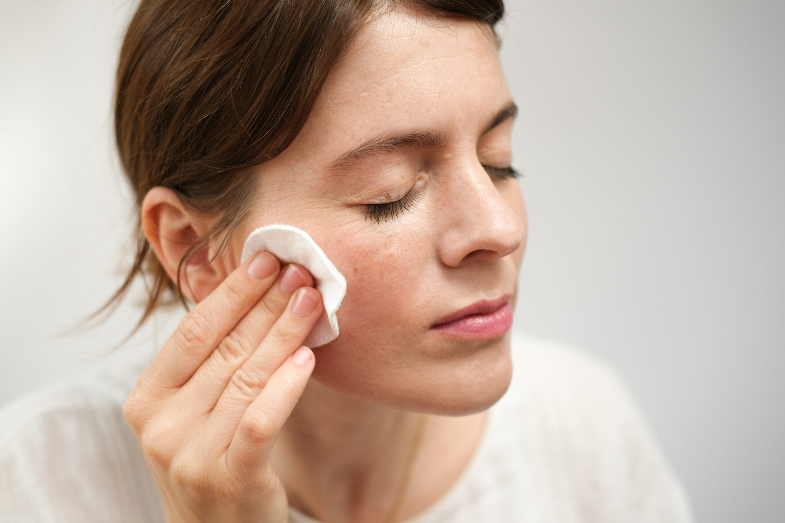 Gesto delicato di skincare consapevole con dischetto di cotone